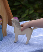 A child's hand holding the Ostheimer white horse. These wooden figures are part of a large range of expertly hand crafted, Waldorf inspired, wooden toys here at Babipur. 
