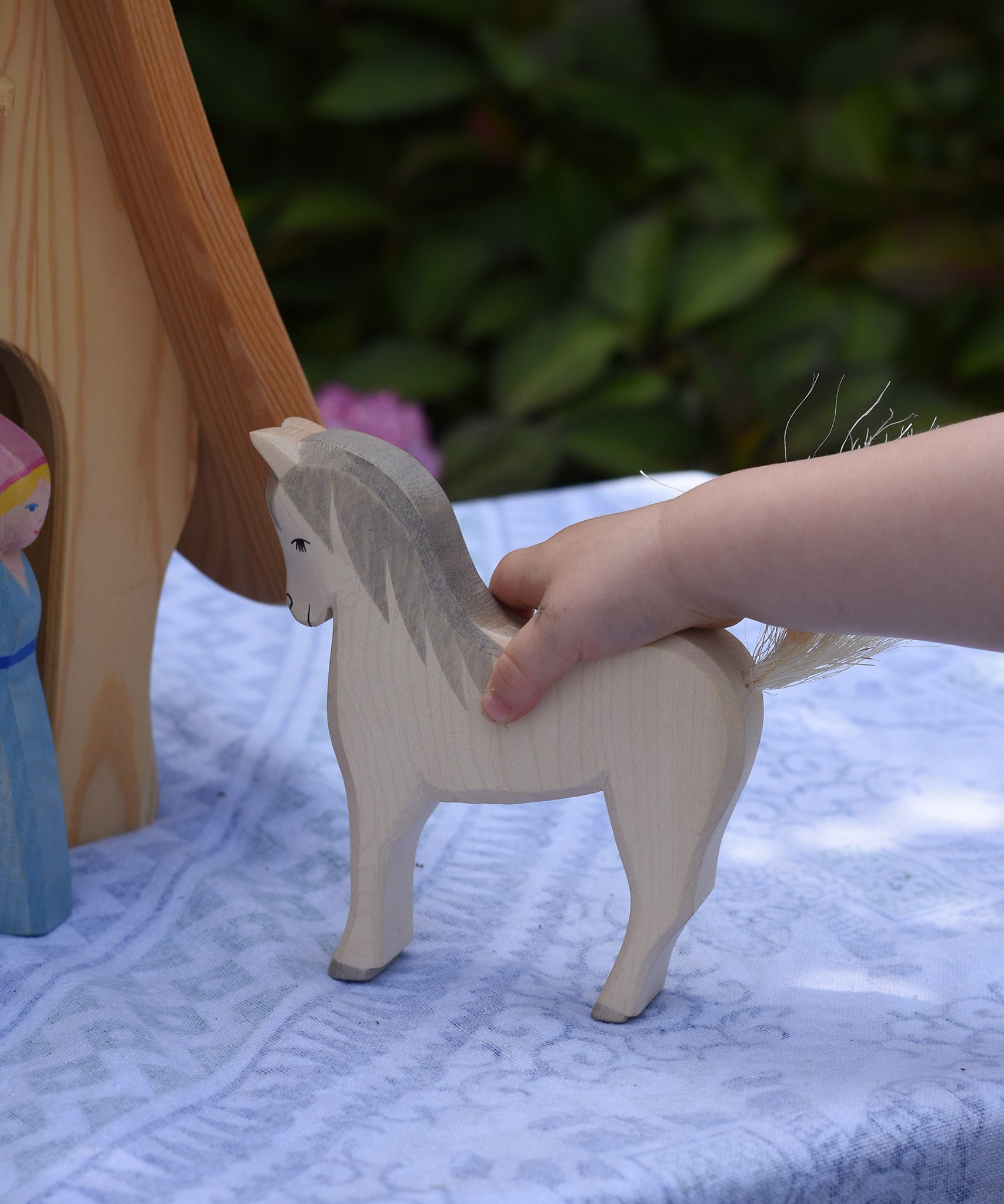 A child's hand holding the Ostheimer white horse. These wooden figures are part of a large range of expertly hand crafted, Waldorf inspired, wooden toys here at Babipur. 

