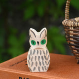 A close up of the Ostheimer white owl wooden toy figure placed on a pile of books. 