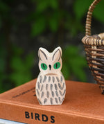 A close up of the Ostheimer white owl wooden toy figure placed on a pile of books. 