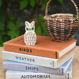 A close up of the Ostheimer white owl wooden toy figure placed on a pile of books. 