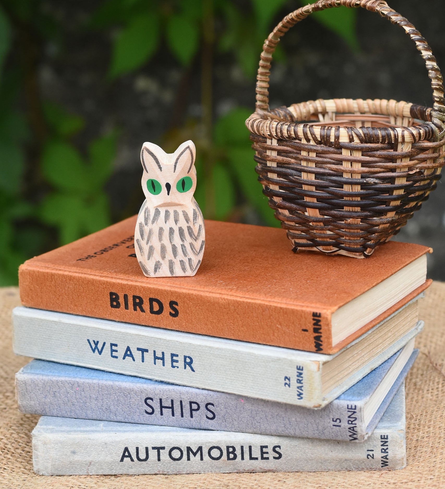 A close up of the Ostheimer white owl wooden toy figure placed on a pile of books. 