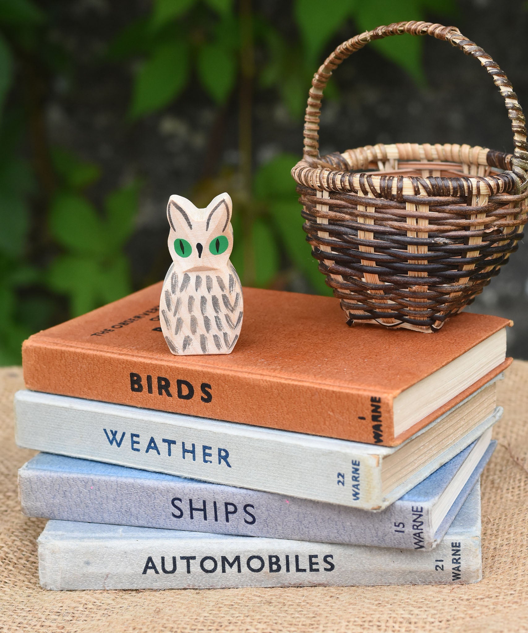 A close up of the Ostheimer white owl wooden toy figure placed on a pile of books. 