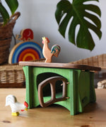 Ostheimer white rooster placed in front of a green hutch with a brown bremer rooster placed on the roof. 