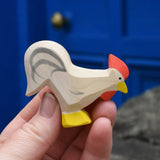 Ostheimer white rooster wooden toy figure in an adult's hand. 