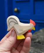Ostheimer white rooster wooden toy figure in an adult's hand. 