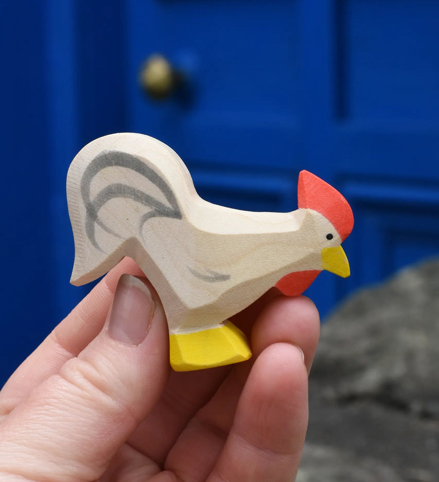 Ostheimer white rooster wooden toy figure in an adult's hand. 