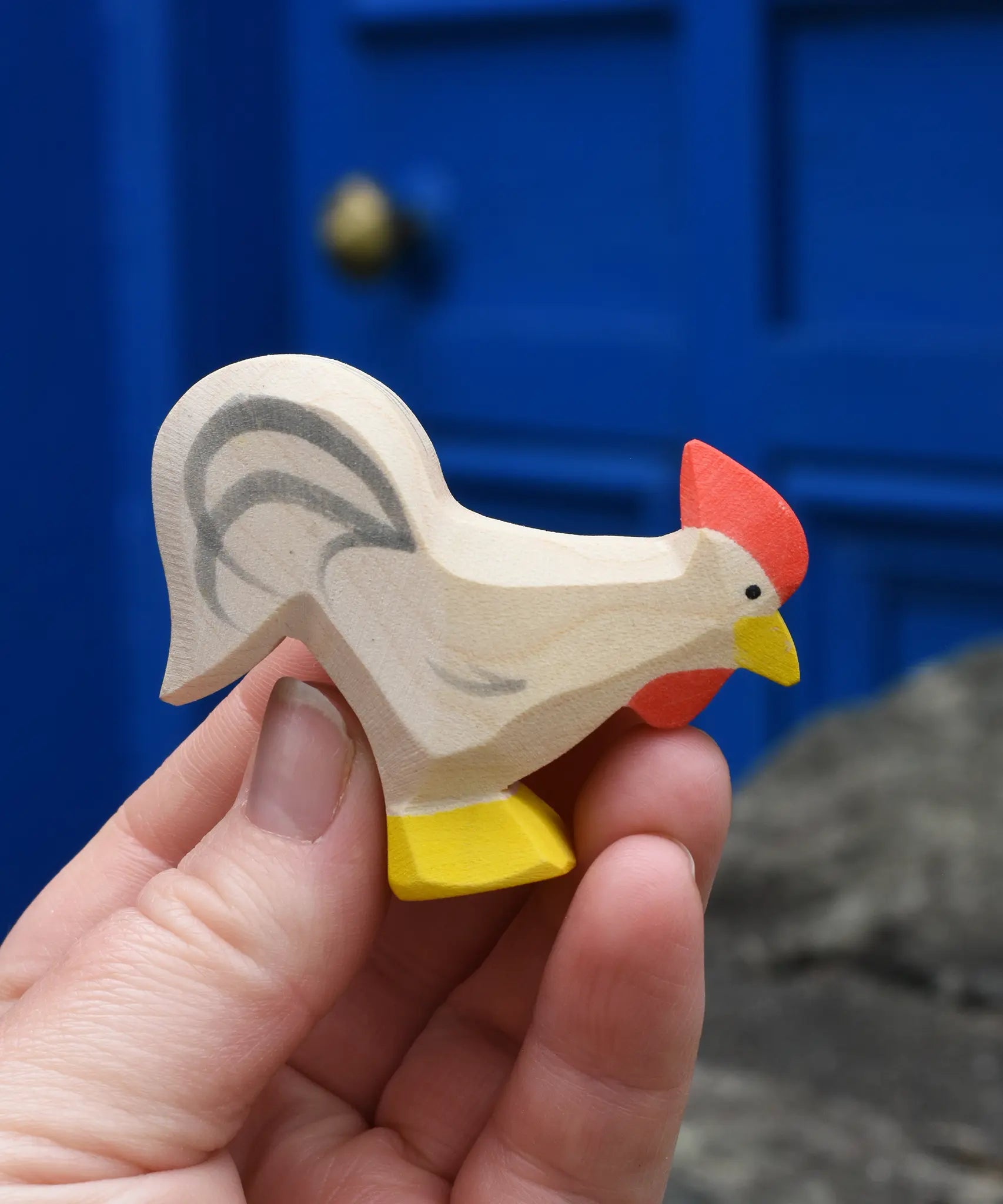 Ostheimer white rooster wooden toy figure in an adult's hand. 