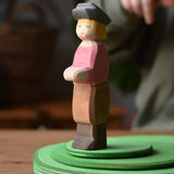 Ostheimer son wooden toy figure placed on a green meadow grass play bases, a child can be seen pointing at it in the background.