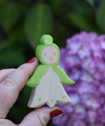 An Ostheimer hand made and hand painted wooden snowdrop Flower Child figure toy held in an adult's hand for scale. These flower child wooden figures are part of a wide range of expertly hand crafted wooden toys here at Babipur. 