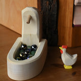 Ostheimer white hen with head up standing besides the white village well filled with Billes marbles.
