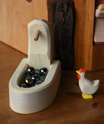 Ostheimer white hen with head up standing besides the white village well filled with Billes marbles.