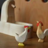 Ostheimer white hen with head up standing in front of the white village well.