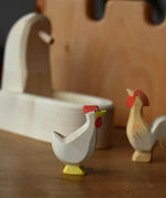 Ostheimer white hen with head up standing in front of the white village well.