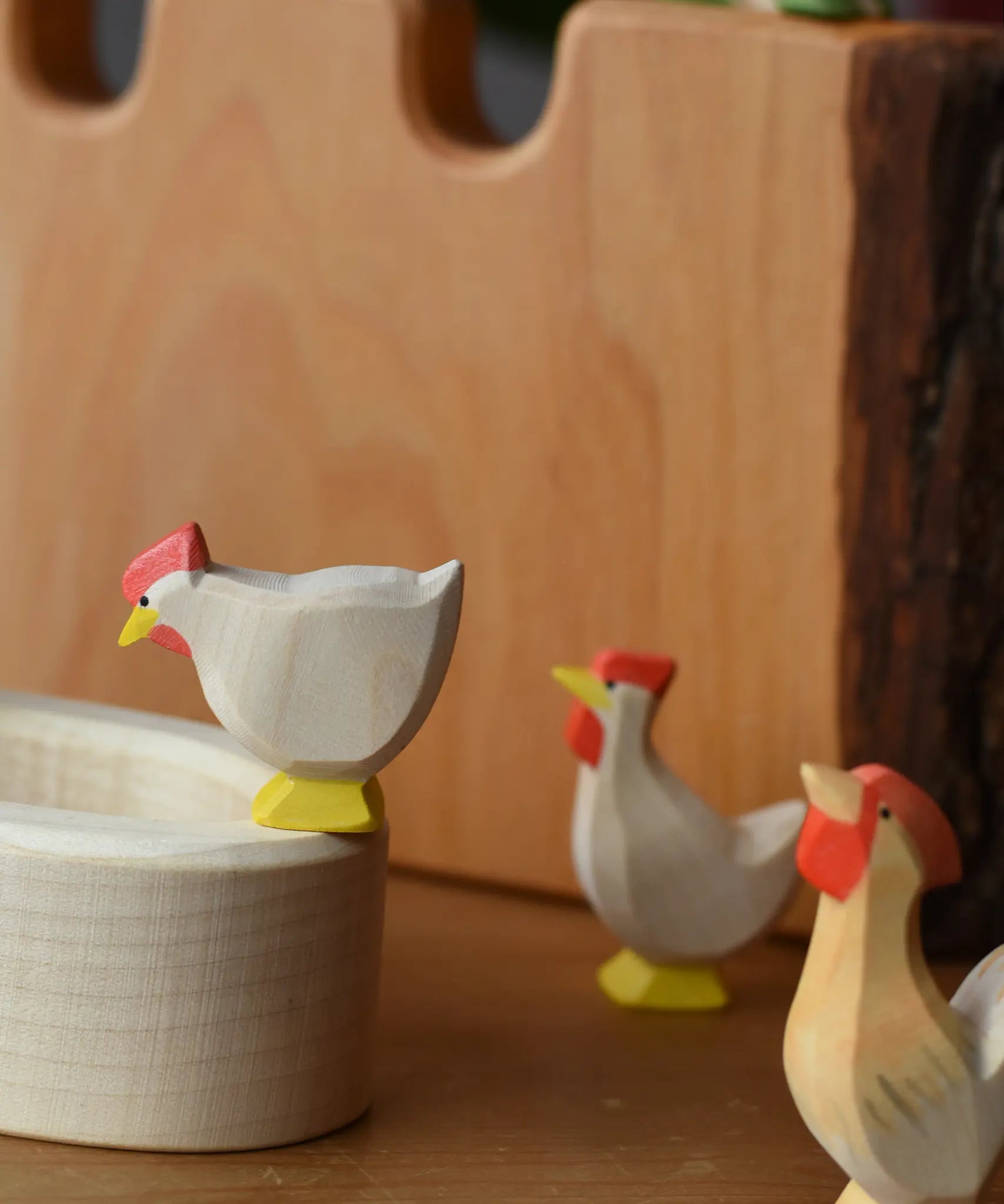 Ostheimer white standing hen placed on the edge of a village well with a hen and rooster standing besides it.