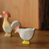 Ostheimer white standing hen placed at the front of a small world play scene with an ochre rooster in the background.