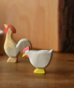 Ostheimer white standing hen placed at the front of a small world play scene with an ochre rooster in the background.