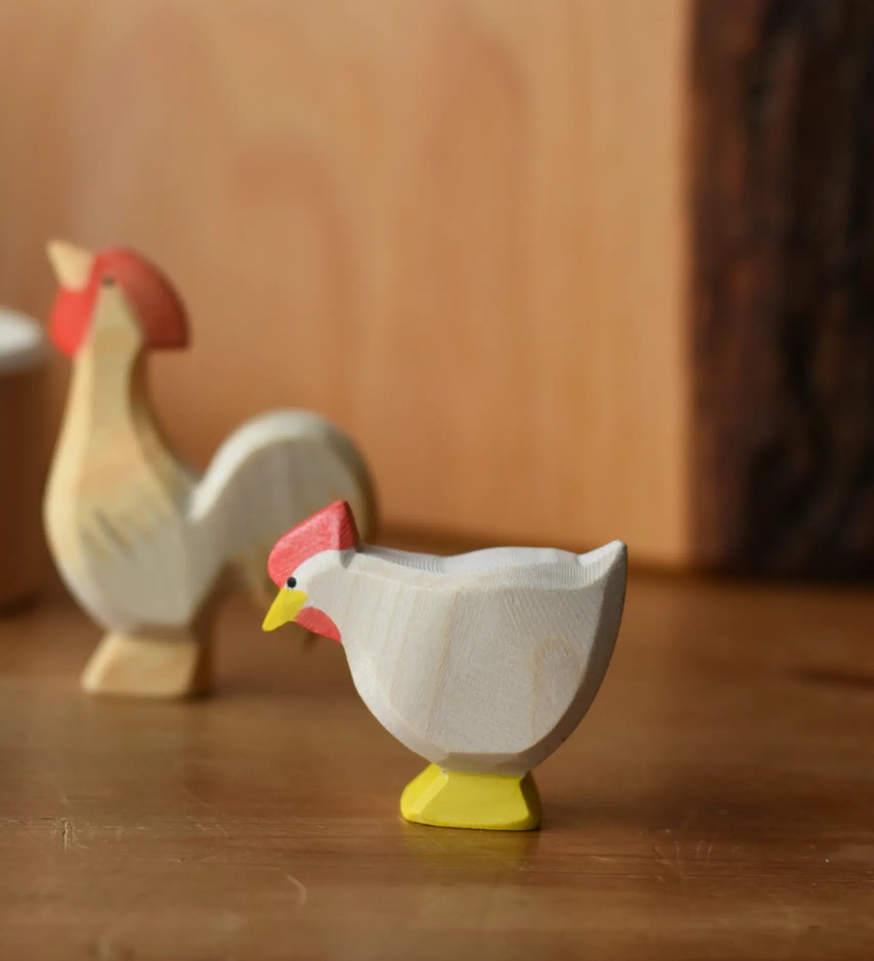 Ostheimer white standing hen placed at the front of a small world play scene with an ochre rooster in the background.