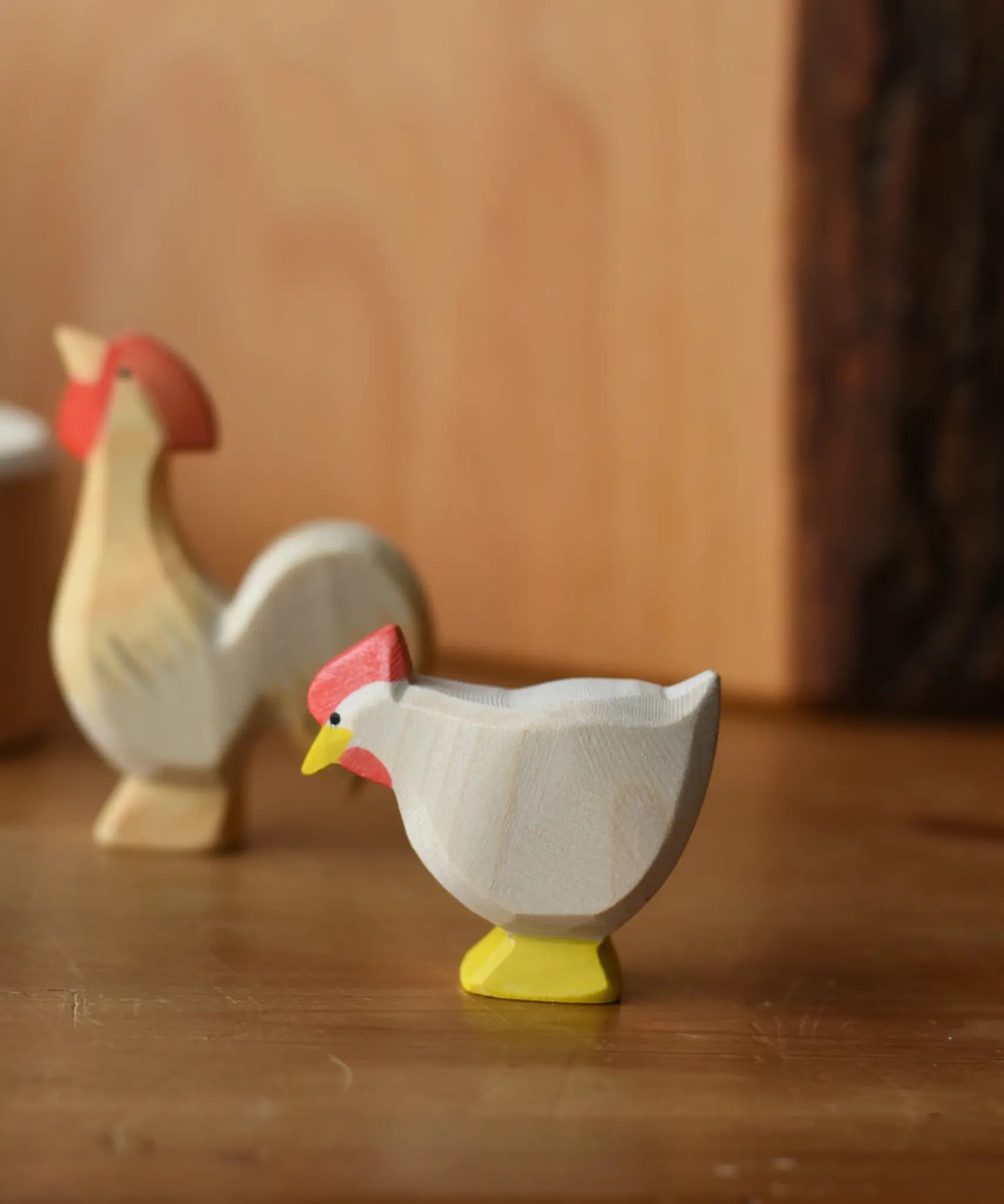 Ostheimer white standing hen placed at the front of a small world play scene with an ochre rooster in the background.