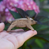 An Ostheimer wild boar piglet figure shown on an adult's hand to show scale. Check out our full range of expertly crafted wooden toy figures and scenery here at Babipur.