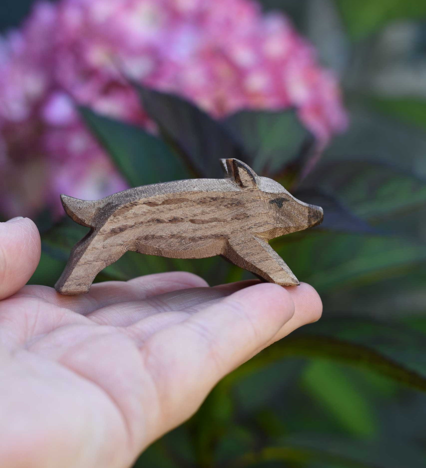 An Ostheimer wild boar piglet figure shown on an adult's hand to show scale. Check out our full range of expertly crafted wooden toy figures and scenery here at Babipur.