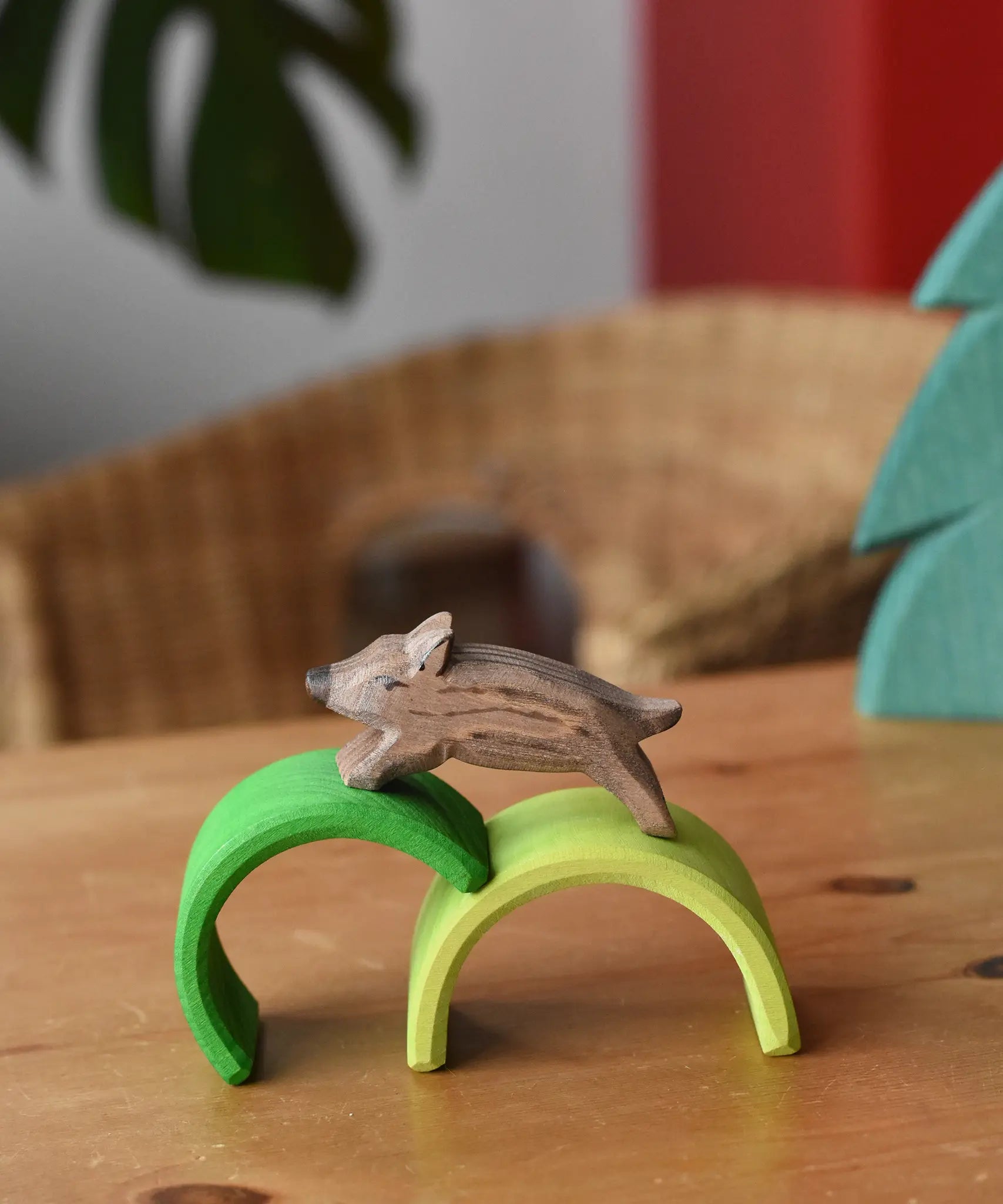 Ostheimer wild boar wooden toy figure placed on green arches from Grimm's mini rainbows. 