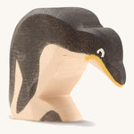 A wooden Ostheimer penguin figure with its head down on a cream background.