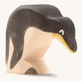 A wooden Ostheimer penguin figure with its head down on a cream background.