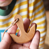 Ostheimer wooden anchor for toy boats on string in an adult's hand.