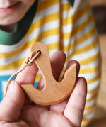 Ostheimer wooden anchor for toy boats on string in an adult's hand.