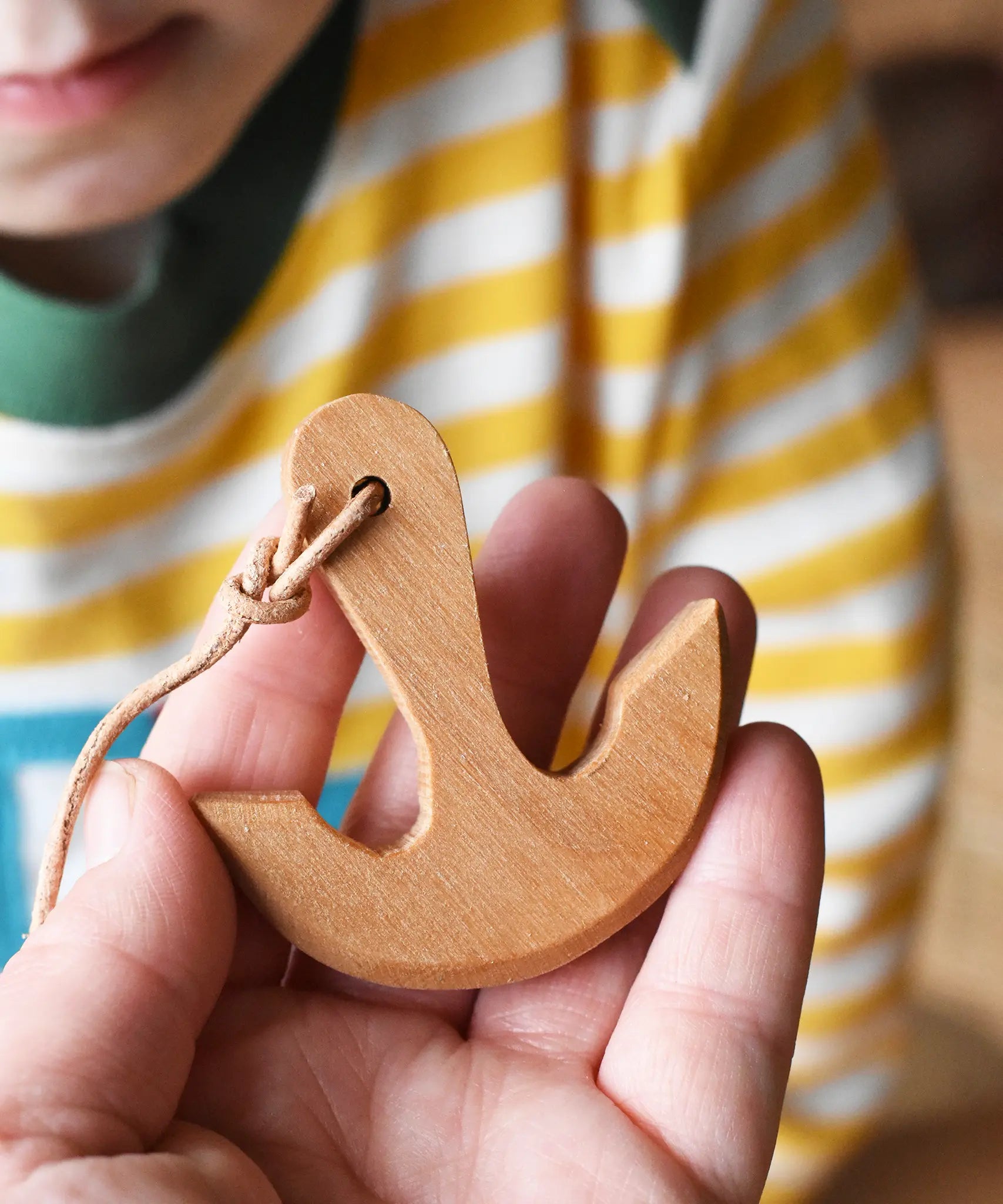 Ostheimer wooden anchor for toy boats on string in an adult's hand.