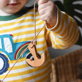 Child holding up the Ostheimer wooden anchor on string. 