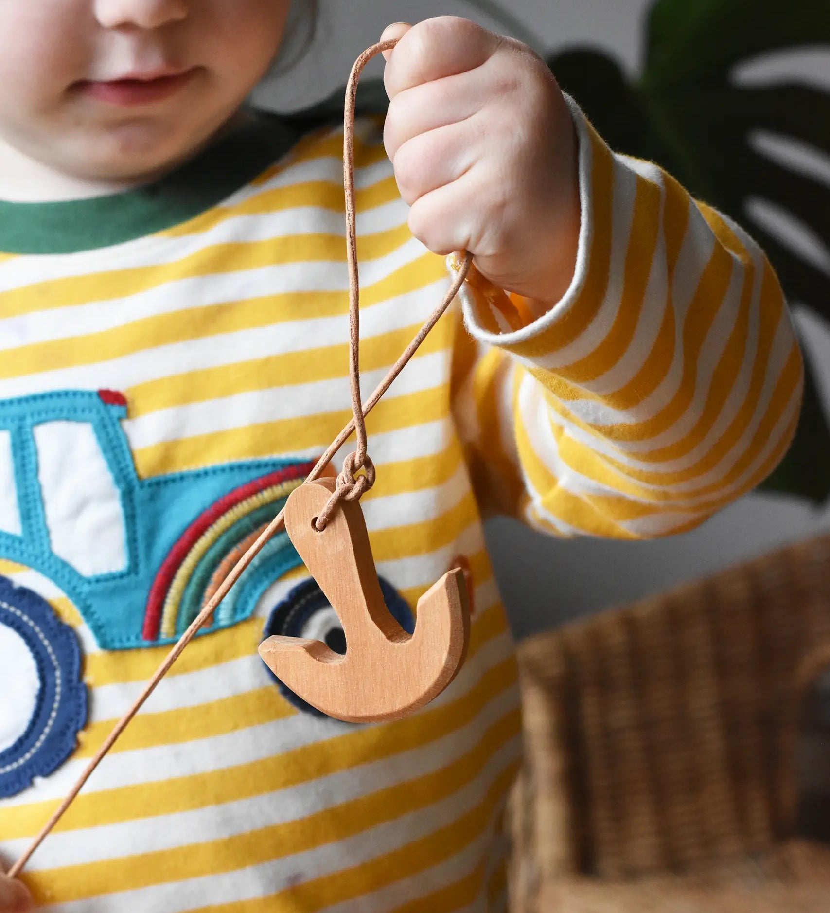 Child holding up the Ostheimer wooden anchor on string. 
