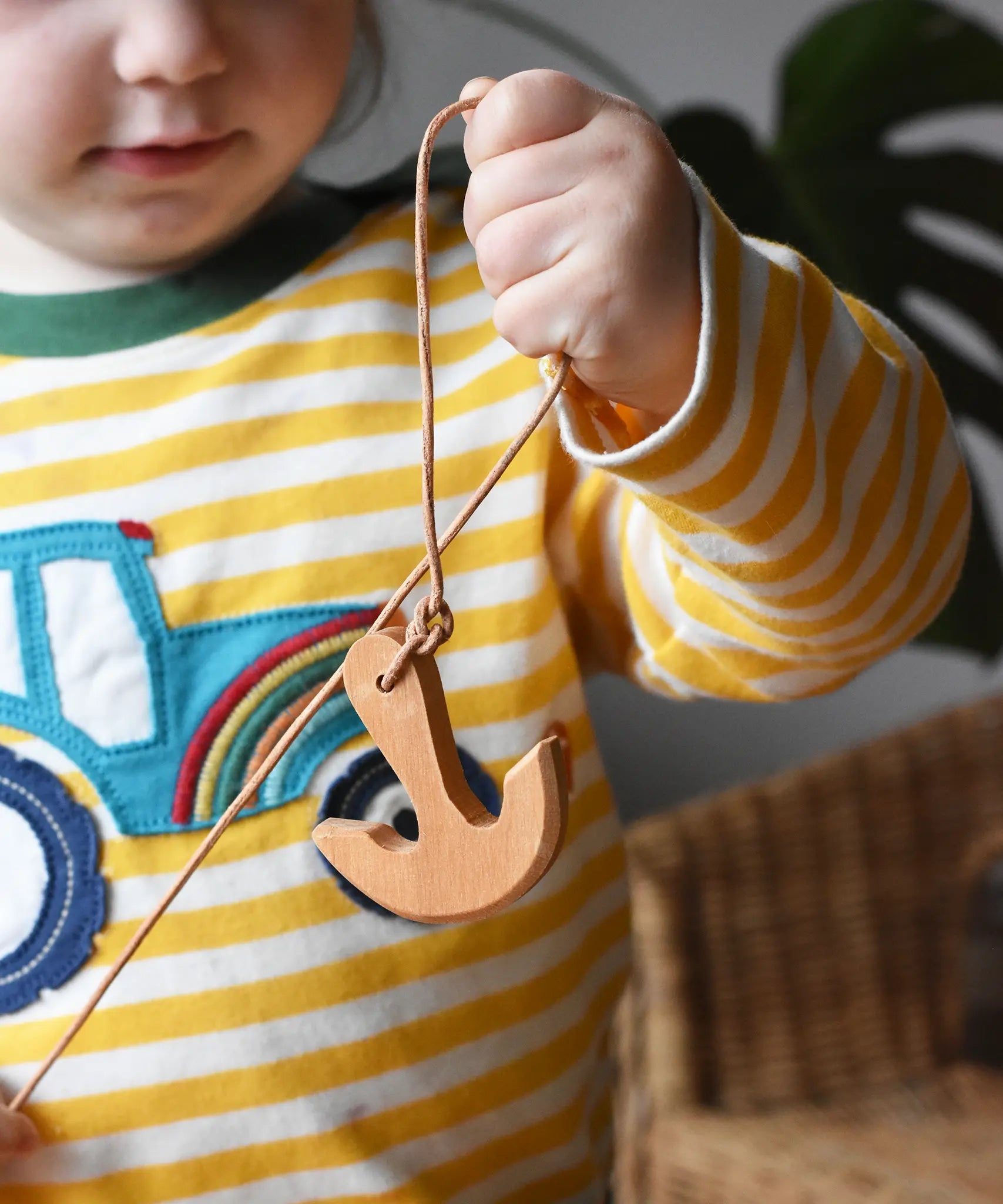 Child holding up the Ostheimer wooden anchor on string. 