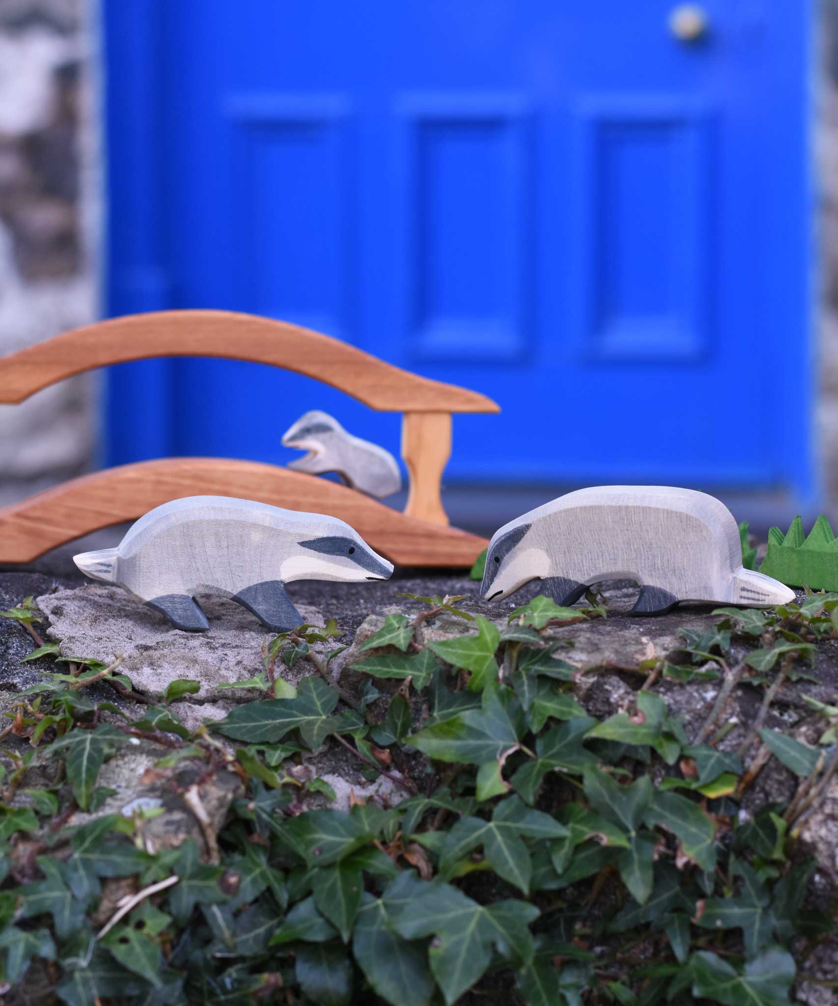 A group of badgers placed in a small world scene set up on a stone wall outdoors. A wide range of wooden animal figures and scenery pieces ca be found at Babipur. 