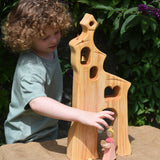 A child playing, standing behind an Ostheimer wooden bell tower. The child is reaching for the princess placed in front of the tower. These wooden figures are part of a large range of expertly hand crafted, Waldorf inspired, wooden toys here at Babipur.