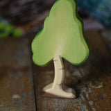 A small Ostheimer birch tree figure placed on a wooden surface. These wooden figures are part of a wide range of expertly hand crafted wooden toys here at Babipur. 
