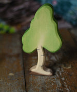 A small Ostheimer birch tree figure placed on a wooden surface. These wooden figures are part of a wide range of expertly hand crafted wooden toys here at Babipur. 