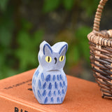 A close up of the Ostheimer white owl wooden toy figure placed on a pile of books. 