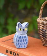 A close up of the Ostheimer white owl wooden toy figure placed on a pile of books. 