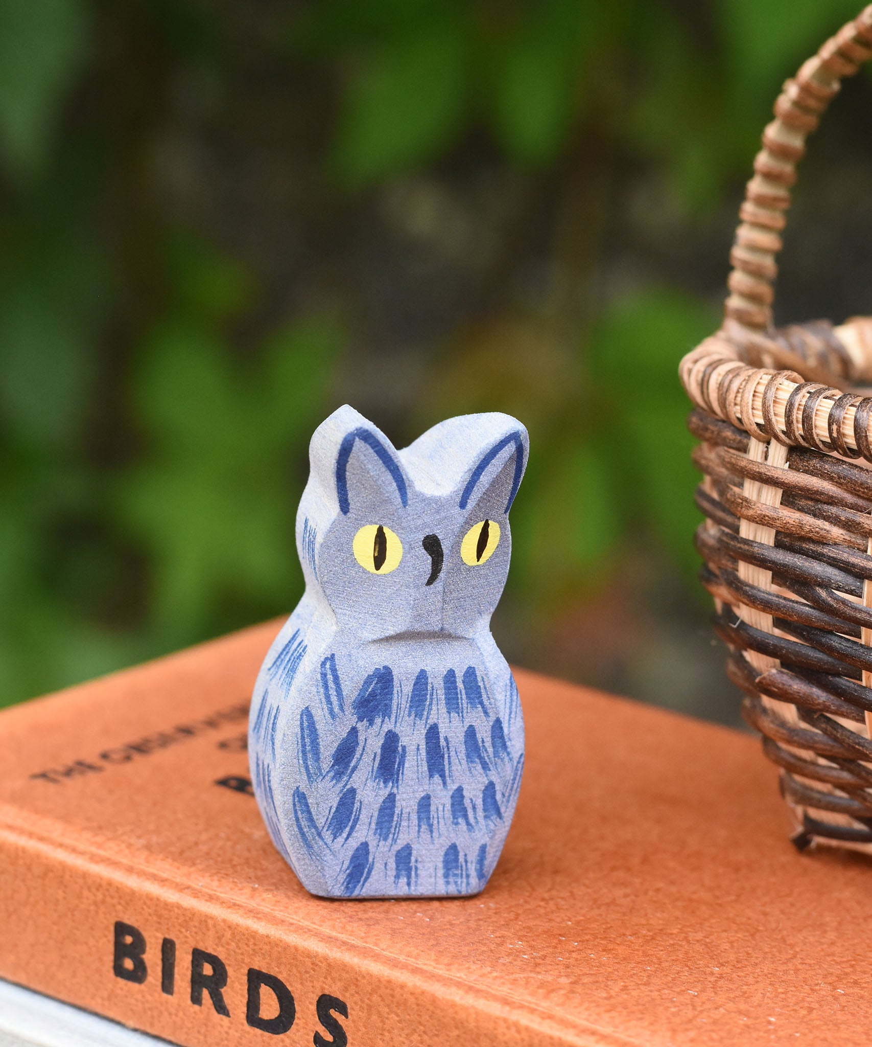 A close up of the Ostheimer white owl wooden toy figure placed on a pile of books. 