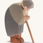 A wooden bowing Ostheimer shepherd holding a staff on a cream background.