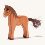 A brown wooden Ostheimer colt figure on a cream background.