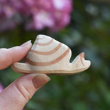 An Ostheimer snail wooden toy figure shown in a n adult's hand for scale. This to figure is part of a wide range of handmade wooden toy figures available at Babipur.