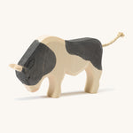 A wooden black and white Ostheimer ox standing on a cream background.