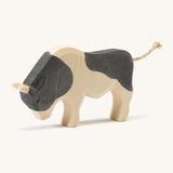 A wooden black and white Ostheimer ox standing on a cream background.