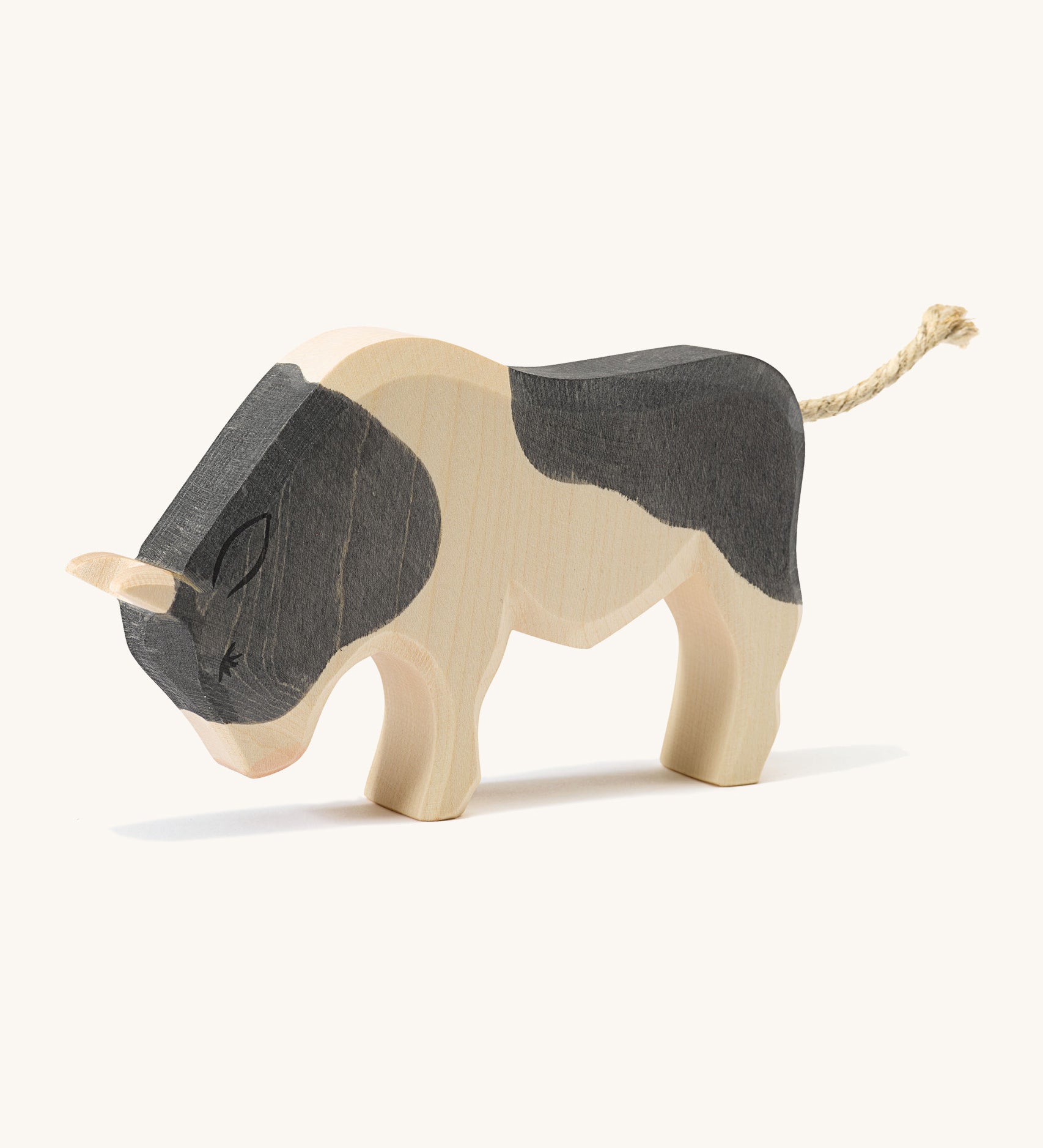 A wooden black and white Ostheimer ox standing on a cream background.