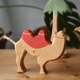 Ostheimer camel with red saddle placing it on a wooden surface with a tall palm tree figure in the background