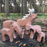 Ostheimer deer stag, a deer eating with a couple of fawns and a standing deer wooden figures gathered together in a natural play scene on tree stump. Handmade in Germany, Waldorf small world toy and sold at Babipu