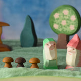 Two Ostheimer dwarves wooden toy figures placed in a small world play scene. The dwarf figures have red and green coloured outfits with matching hats and a long white beard. The figures have been placed on a green coloured Ostheimer play scarf. These wooden figures are part of a large range of expertly hand crafted, Waldorf inspired, wooden toys here at Babipur. 